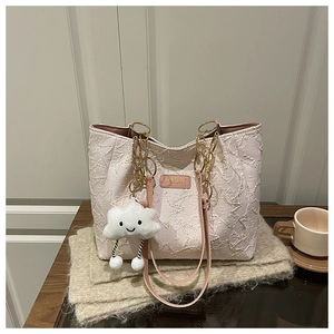 Detail of light pink tote bag with star pattern, plush cloud charm and metal chain strap