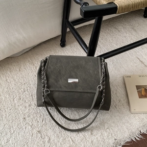 Olive green suede tote bag with silver chain strap and metal buckle on plush rug