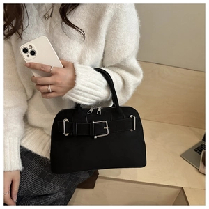 Detail of black suede handbag with decorative buckle and silver hardware in lifestyle shot