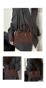 Detail view of dark brown suede tote with metal buckle and shoulder strap worn with a blazer