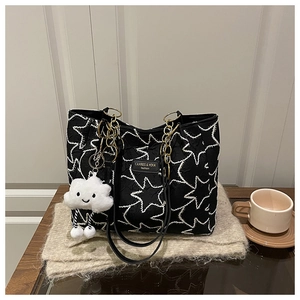 Detail of a black star-print tote bag with gold chain strap and plush cloud pendant