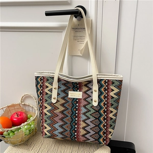 Ethnic tote bag with colorful zigzag patterns and fashion label hanging on a white door