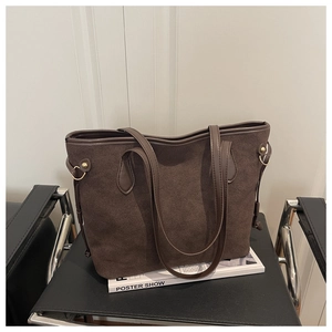 Detailed close-up of dark brown suede tote bag with smooth leather trim and gold metal buckles
