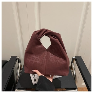 Detail view of burgundy leopard print tote bag with twisted handle and matte leather finish