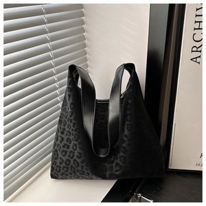 Detail of glossy black leopard pattern tote bag on a window sill with natural lighting