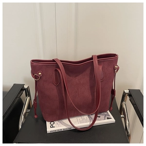Detail of burgundy frosted suede tote bag with drawstring side and gold hardware accents