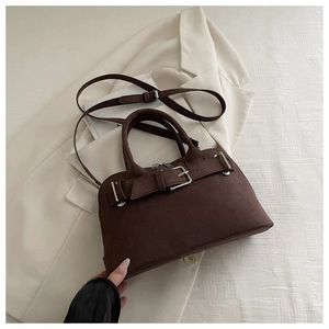 Close-up of deep brown suede handbag featuring a silver buckle and round handles