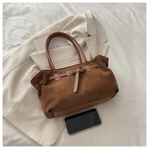 Detail of brown suede tote bag featuring silver metal buckle and reinforced leather handle