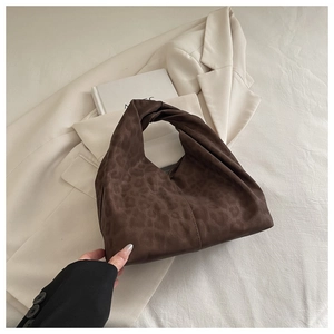 Detail of leopard print suede handbag featuring a unique twisted knot handle design