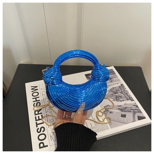 Detail of blue electroplated crescent bag with knotted handle and gold chain strap