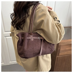 Detail of dark brown suede tote bag featuring slim leather straps and buckle strap details