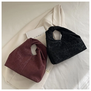 Close-up of leopard print knot handbags in burgundy and black with satin texture
