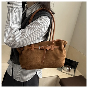 Macro detail of caramel suede tote bag with decorative buckle and premium texture