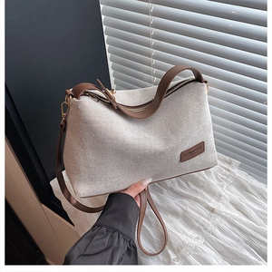 Detail of woven fabric handbag with brown leather strap and metal zipper closure