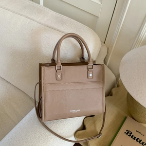 Borsa tote marrone vintage con manico superiore su uno sfondo di divano minimalista