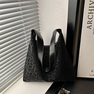 Minimalist large black leopard print tote bag with wide shoulder strap on a sunlit windowsill