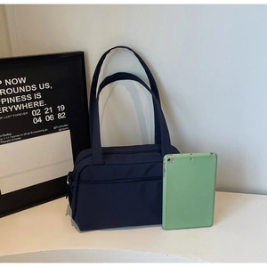 Detail of dark blue nylon tote bag showing zipper pocket and size compared to tablet