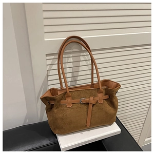 Detailed close-up of brown suede tote bag with leather belt buckle and metal pin