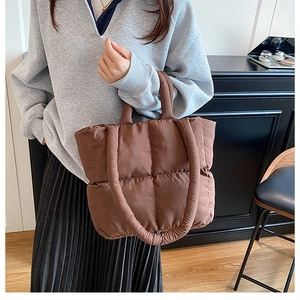 Detail of the brown quilted puffer tote bag featuring soft handles and padded nylon texture