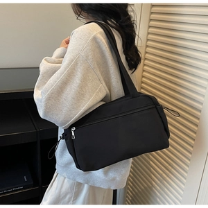 Detail of minimalist black nylon tote bag with zipper pocket and side drawstring accents