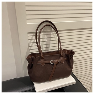 Detail of a brown suede tote bag featuring a leather strap and metallic buckle detail
