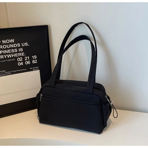 Close-up of a black minimalist tote bag with zipper pocket and side drawstring compartments