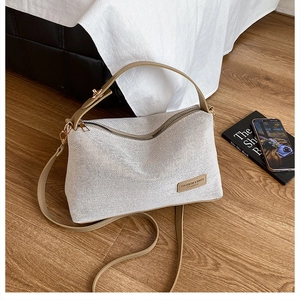 Detail of woven fabric handbag with leather strap and fashion label on wooden floor