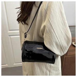 Détail du sac bandoulière en cuir verni noir avec logo FASHION doré et ferrures en métal
