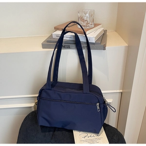 Detail of navy blue nylon tote bag with front zipper pocket and long shoulder straps
