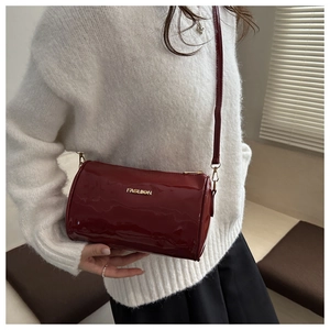 Close-up of wine red patent leather cylinder bag featuring a gold FASHION logo detail