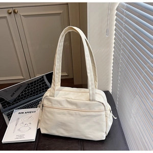 Detail view of cream canvas tote bag with wide handles and front zipper pocket for daily use