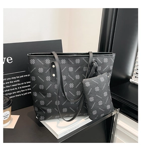 Detail view of black tote bag set with clover print on books with coffee cup context