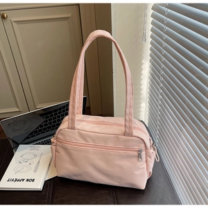 Detail view of pink canvas shoulder bag with multiple zippers and long straps for commuting