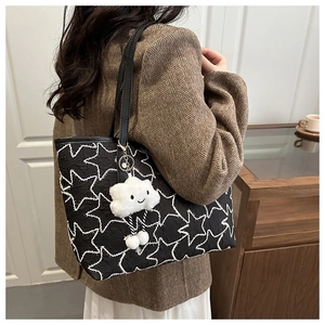 Detail of star-patterned tote bag with plush cloud charm on brown wool blazer