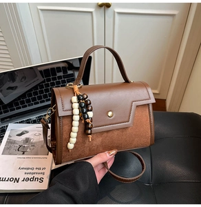 Detail of a brown PU leather crossbody bag with wooden beads on a leather sofa