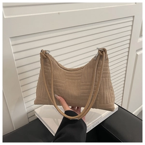 Détail macro du sac bandoulière en velours côtelé marron avec gaufrage géométrique et anneaux
