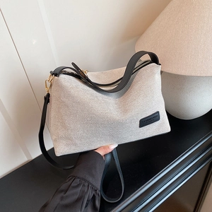 Minimalist cream canvas tote bag with black leather trim and gold zipper for women