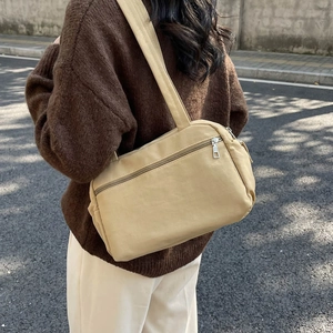 Minimalist beige nylon tote bag for women showing a spacious casual shoulder bag outdoors