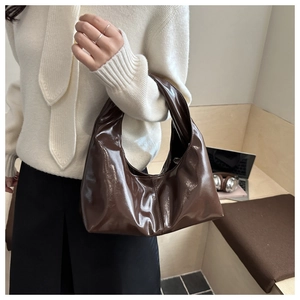 Detail of a dark brown glossy hobo bag shown from a 45-degree angle in a casual setting