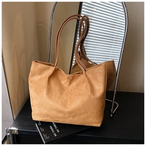 Detail shot of brown suede tote bag with slim handles and matte leather texture