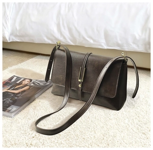 Close-up of vintage brown PU leather texture and gold buckle on a stylish crossbody bag