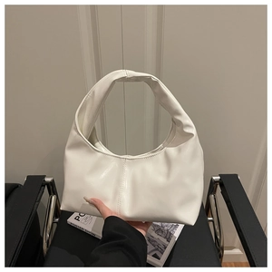 Close-up of minimalist white leather shoulder bag with sleek curved structure and stitching