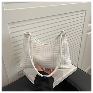Détail de la texture tressée du sac blanc avec anneau en métal argenté et fermeture éclair
