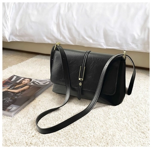 Detail shot of black faux leather texture with golden hardware on retro crossbody bag