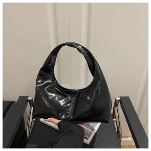 Detailed close-up of a glossy black crescent hobo bag with smooth patent leather finish