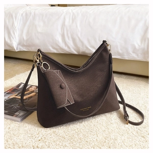 Close-up of matte leather texture with white contrast stitching on a dark brown bag