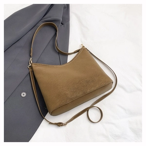 Close-up of brown suede tote bag with adjustable metal buckle and fine stitching detail