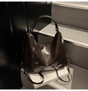 Detail of dark brown glossy leather tote bag with vertical zipper and adjustable strap
