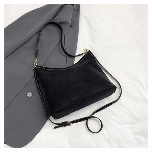 Close-up of black faux suede shoulder bag with white contrast stitching and gold buckle