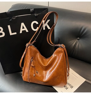 Detail of vintage brown leather bag with glossy texture and vertical zipper pocket